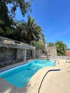 a swimming pool in a yard with a stone wall at Casas Arraial in Arraial do Cabo