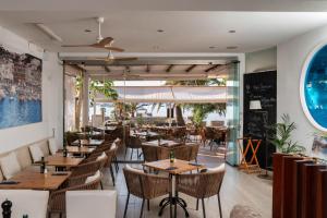 a restaurant with wooden tables and chairs and a large window at Hotel Capri Pollensa in Port de Pollensa