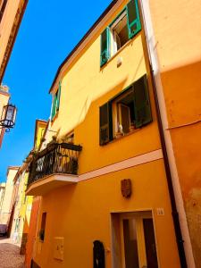 a yellow building with green shutters and a balcony at Ca' Letizia in Noli