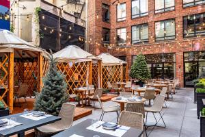 eine Terrasse mit Tischen und Stühlen und ein Gebäude in der Unterkunft Arlo SoHo in New York