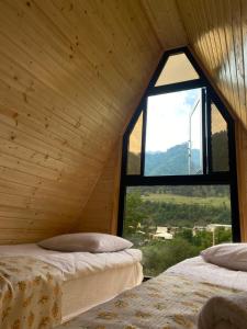 two beds in a wooden room with a window at khedi cottage in Mestia