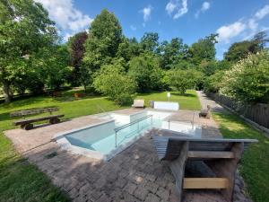 ein Schwimmbad in einem Park mit zwei Bänken in der Unterkunft Schlossalm Ferienwohnungen in Brannenburg