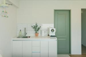 a kitchen with white cabinets and a green door at 버터인 강릉역 중앙시장 월화거리 교리단길 도보 10분 in Gangneung +26 photos