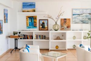 a living room with white furniture and paintings at Hotel Capri Pollensa in Port de Pollensa