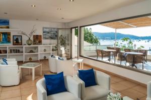 a living room with white chairs and a large window at Hotel Capri Pollensa in Port de Pollensa