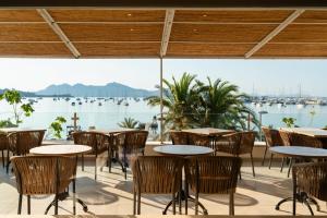 a patio with tables and chairs and a view of the water at Hotel Capri Pollensa in Port de Pollensa +39 photos
