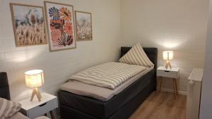 a small bed in a room with two tables and two lamps at Apartment 2 Unter den Eichen in Tätendorf-Eppensen