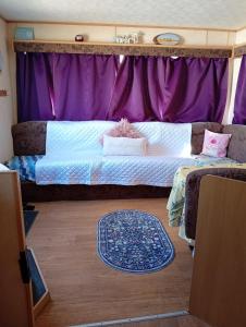a bedroom with a large bed and purple curtains at Sunrise Caravan in Dymchurch