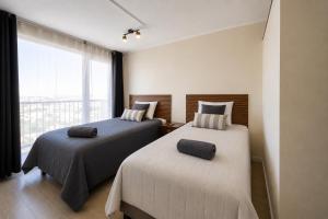 two beds in a room with a large window at Suite moderna espacio parque in Calama