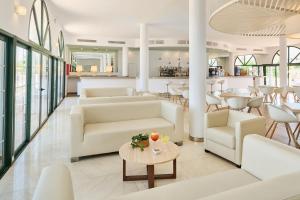 a lobby with white couches and a table at Grupotel Mar de Menorca in Es Canutells