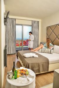 two people are sitting on beds in a hotel room at Olympus Thea Boutique Hotel in Platamonas