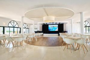 a dining room with white tables and white chairs at Grupotel Mar de Menorca in Es Canutells