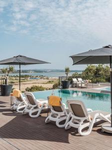 a group of chairs and umbrellas next to a swimming pool at Hillside House Residence in Foz do Arelho
