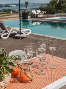 a table with wine glasses on a table near a swimming pool at Hillside House Residence in Foz do Arelho