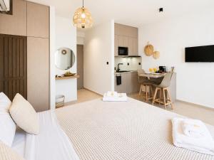 a white bedroom with a large bed and a kitchen at AVENA Suites in Kato Gouves