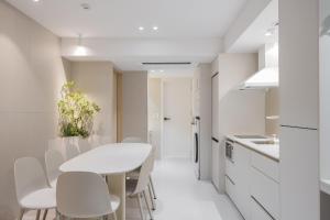 a white kitchen with a white table and chairs at 더하다 in Busan