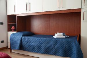 a bed with a blue blanket and white cabinets at Three Tails House in Capezzano Pianore,