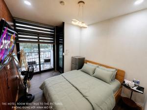 a bedroom with a bed and a tv and a window at Khách Sạn MINTNACIE in Phan Rang–Tháp Chàm