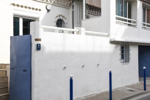 a white building with a blue door on a street at Villa Faraman au bord de l'eau in Le Grau-du-Roi