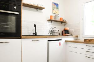 a kitchen with white cabinets and black appliances at Villa Faraman au bord de l'eau in Le Grau-du-Roi