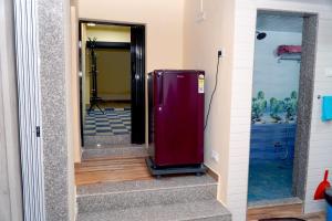 a red refrigerator in a hallway with a mirror at Sitara Homestay in Ratnagiri
