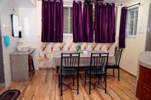a dining room with a table with chairs and purple curtains at Sitara Homestay in Ratnagiri