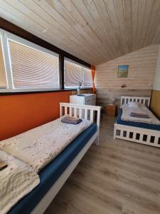 two beds in a room with wooden walls and windows at penzion U Hájků in Křepice +33 photos