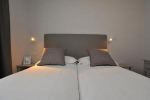 two beds in a hotel room with white at Condhotel Fanti Ski & Bike in Valdisotto