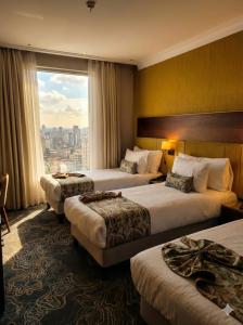 a hotel room with three beds and a large window at Hôtel Saint Eugène in Bab el Oued