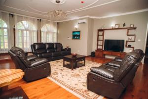 a living room with leather furniture and a flat screen tv at Kilimanjaro pazuri summit villas 1 in Msaranga