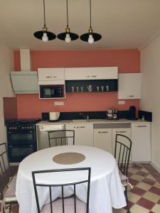 a kitchen with a white table and chairs in it at Le Refuge du Phare in Saint-Vivien-de-Médoc