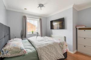 a bedroom with a bed and a tv on the wall at Bright Double Room with Shared Bathroom in Luton