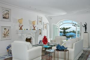 a living room with white chairs and a fireplace at Hotel La Minerva in Capri