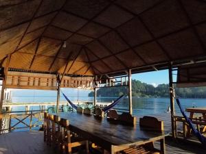 a wooden table with hammocks on a boat on the water at Losmen Togean Wisata in Pulau Togian
