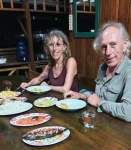 a man and woman sitting at a table with plates of food at Losmen Togean Wisata in Pulau Togian