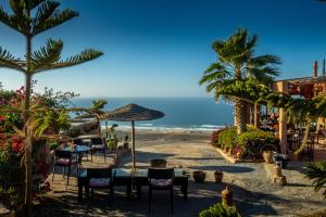 a table and chairs with the ocean in the background at Le Nid d'Aigle in Mirleft +12 photos