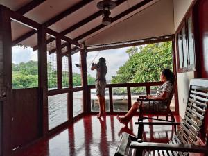 a man standing on a porch looking out at a woman at Yasindu Riverfront Villa in Balapitiya