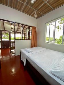 a bedroom with a large bed in a room with windows at Yasindu Riverfront Villa in Balapitiya