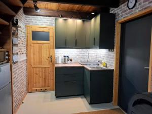 a small kitchen with green cabinets and a door at Śledziowy Domek 