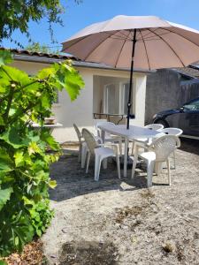a white table and chairs with an umbrella at Le Refuge du Phare in Saint-Vivien-de-Médoc +3 photos