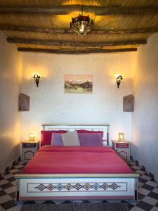 a bedroom with a red bed with a chandelier at Le Nid d'Aigle in Mirleft