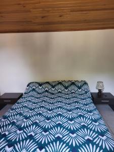 a bed with a blue and white comforter on it at Le Refuge du Phare in Saint-Vivien-de-Médoc