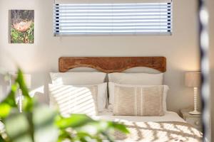 a bedroom with a bed with white pillows and a window at Chapmans Corner Studio in Noordhoek