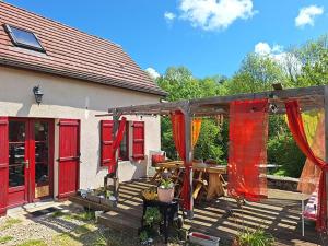 a backyard with red doors and a wooden deck at Gite Fée Grenouille in Martigny-le-Comte