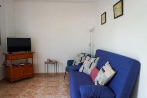 a living room with a blue couch and a tv at Casa Argelio in Alojera