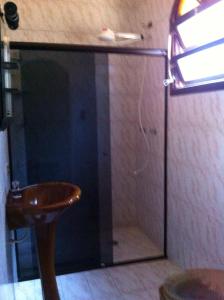 a bathroom with a glass shower with a wooden toilet at No Centro com Piscina Aquecida solar in Peruíbe