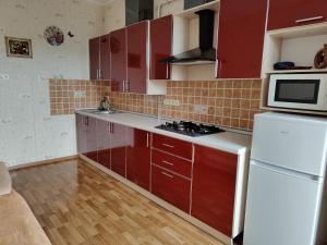 a kitchen with red cabinets and a white refrigerator at Apartment Ekaterina in Chornomorsk