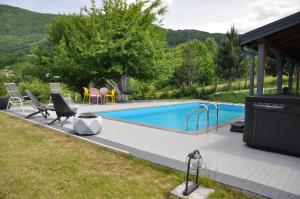 a swimming pool with chairs and a table next to it at Villa Saraj with Swimming Pool & Jacuzzi near Sarajevo in Sarajevo