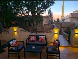 a patio with a couch and chairs and lights at Three Cities Haven in Taʼ Penza