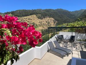 a balcony with two chairs and red flowers with a view at Calheta Suites - Vinha & Jardim - Adults-only suites met hottub & zeezicht in Calheta
